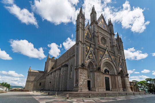 Italy - Orvieto - Duomo di Orvieto - Wide angle view of the massive striped side facade and apse under a cloudy sky