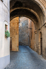 Italy - Orvieto - Orvieto Old Town - Stone archway spanning across a quiet medieval street