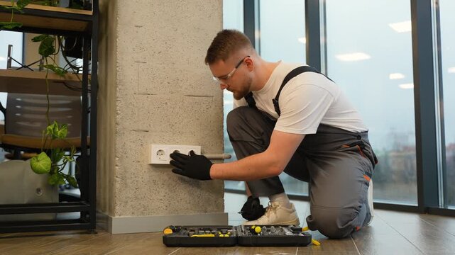 Professional electrician installing new wall power socket