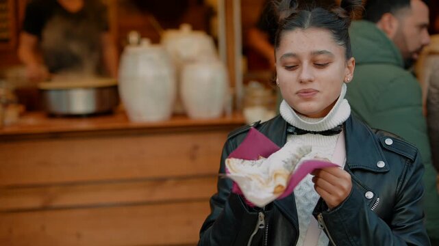 Woman delightedly savors pastry amid bustling market scene