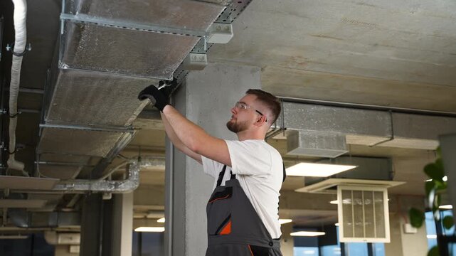 Technician installing ventilation system ductwork in a modern office