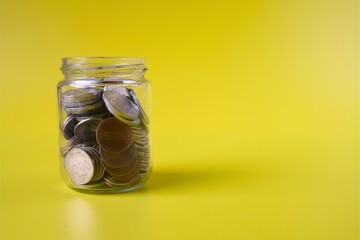 jar containing coins on yellow background