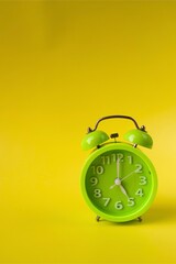 Green alarm clock on yellow background
