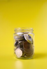 jar containing coins on yellow background