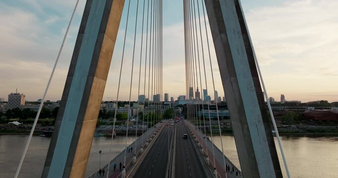 Aerial Warsaw skyline seen through symmetry of Swietokrzyski Bridge at sunset. Vistula riverfront cityscape, and iconic city landmarks. Cinematic 4K drone footage ideal for travel and urban projects