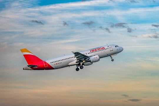 Iberia Airbus A320 taking off into colorful evening sky