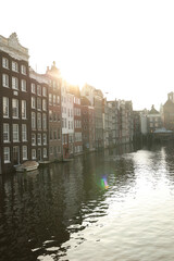 Fototapeta premium Amsterdam canals at sunset with warm light and reflections.