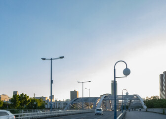 夕暮れのアーチ橋と街灯、遠景の都会のビル群