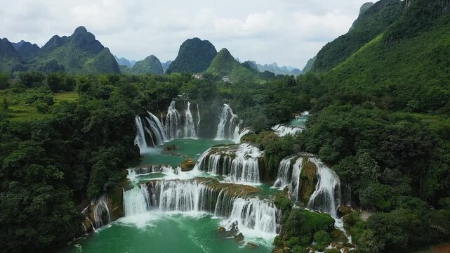 Aerial view of Ban Gioc Waterfall cascading through lush green mountains and dense forest, creating a dramatic natural landscape in northern Vietnam.