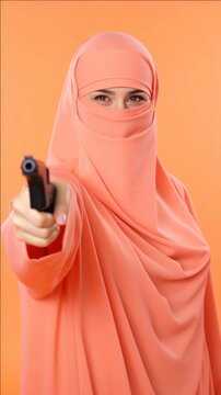 A young Muslim woman in a hijab holding a pistol, seemingly aiming it forward. The is likely to provoke discussion on the intersection of faith