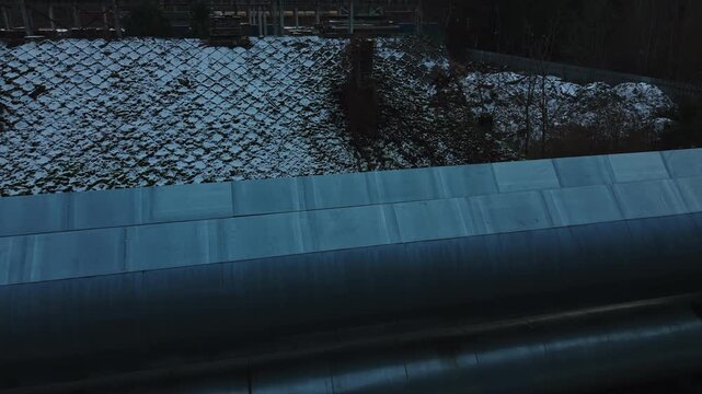 Aerial perspective showcasing twin pipelines navigating snowy terrain amid forested environment for planning