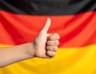 Hand showing thumbs up gesture in front of the German flag.