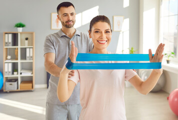 Positive woman working out with personal trainer in the gym. Engaged in a stretch exercise using rehabilitation fitness equipment, fitness under the skilled guidance of a skilled coach or instructor.