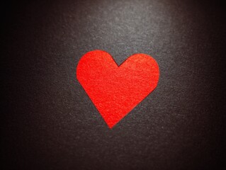 Obraz premium Red Heart Symbol on Black Textured Background, Warm Ambient Glow, Soft Diffused Lighting, Minimalist Composition