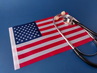 The image displays a stethoscope resting on a small American flag