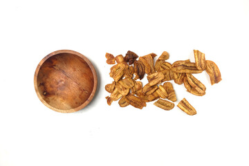 Caramel banana chips scattered near bowl isolated on white background