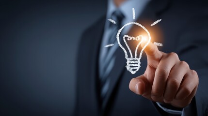 A business professional pointing towards an illuminated lightbulb drawing, symbolizing an idea and innovation. The setting is modern and professional