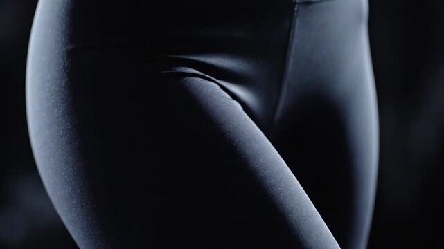 Close-up view of dark spandex leggings with elastic waistband, showcasing smooth texture and form on an unseen figure.