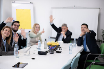 Out of focus group of professionals smiling and waving during a meeting in a modern office