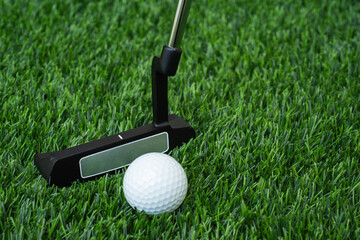 Golf ball and putter club close up view on the green