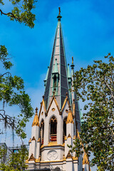 Cathedral of St. John the Baptist steeple, Savannah, framed by green trees.