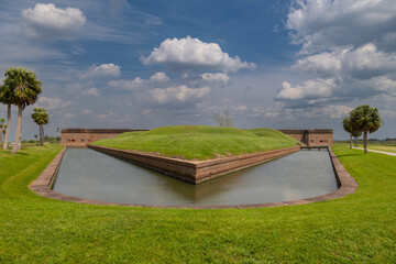 Fort Pulaski: Moated brick fort, green grounds, cloudy sky.