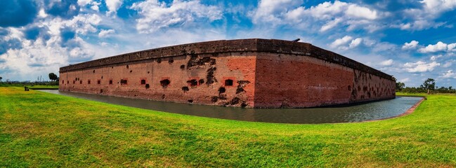 Fort Pulaski: Damaged brick fort, moat, green landscape, blue sky.