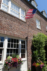 Historic Charleston house with American flag and colorful flowers.