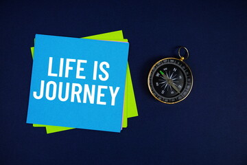 Life Is Journey text written on sticky note with compass on blue  background