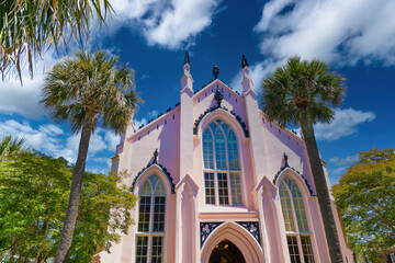 Pink French Huguenot Church, Charleston, framed by palms and blue sky.