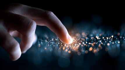 Close-up of a finger pointing towards a glowing cluster of light particles with a dark background. The scene suggests interaction