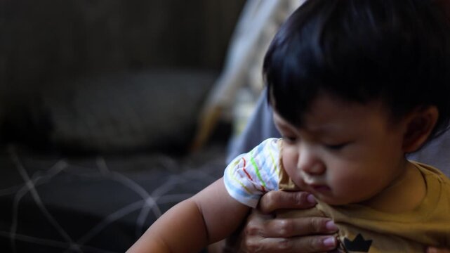 Mother Holding Baby On Lap, A professional documentary clip of mom cradling infant on lap, gentle rocking with heartbeat sync, ideal for parenting intimacy film or quiet affection documentary.