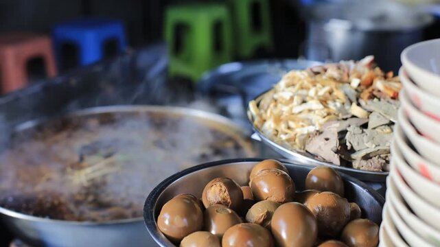 The video background shows Tawan cooking over a charcoal stove, the aroma enticing and delicious, the kind of noodle soup or kway chap commonly sold in tourist areas.