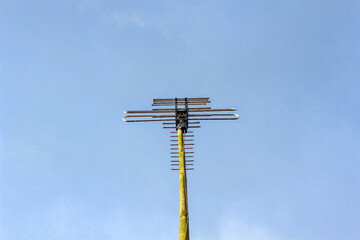 Obraz premium Classic analog television antenna mounted on a pole against clear blue sky, signal reception and telecommunication technology concept, broadcast media and home entertainment equipment