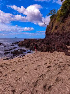 Woman Standing on Rocky Beach with Cliffs and Ocean View
