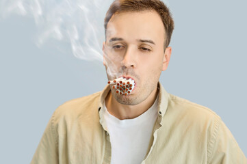 Man smoker with cigarettes displays addiction harm. A dense bundle at his lips illustrates nicotine dependence and extreme smoking, signaling health risk. Bad habit and abuse problem concept. 
