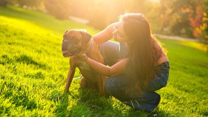 Woman bonding with boxer dog in sunny park grass