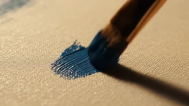 Close-up of a paintbrush applying blue paint to a textured surface.