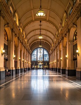 Grand Hallway of a Historic Building with Arched Ceilings and Ornate Lighting.