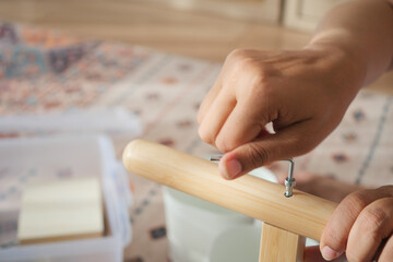 Hand is tightening a screw on a wooden frame