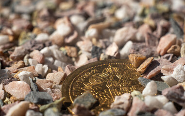 An antique gold coin sticks out of the stones on the road.Find gold on the road.
