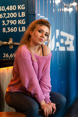 Cute girl in a pink city sweatshirt on a bar stool in a cafe