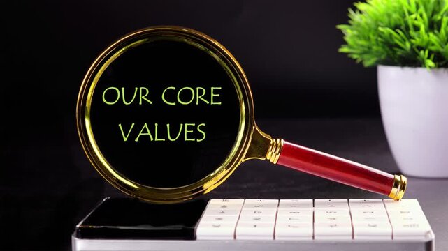 Our core values symbol. Concept words OUR CORE VALUES appear on a black background through a magnifying glass