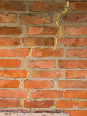 Obraz premium Crack in Red Brick Wall with Yellow Repair Compound