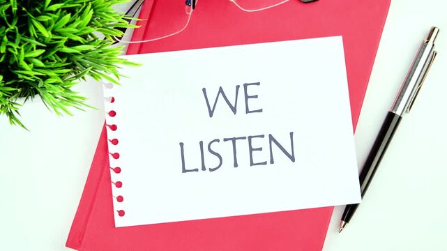 The appearance of the conceptual phrase WE LISTEN on a piece of paper