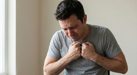 Young man sitting alone and expressing distress at home  