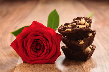 homemade heart shaped chocolate cookies in stack with red rose on wood table