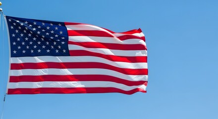 Fototapeta premium USA flag waving majestically in the breeze against a clear blue sky, embodying national pride and the spirit of freedom for Independence Day concept