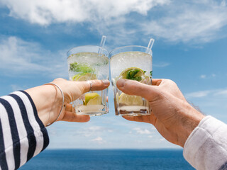 Men's and women's hands and glasses with drinks. Cruise ship deck. Against the backdrop of sea waves. Vacation and travel concept. Chill lifestyle, luxury travel. Perfect for holiday and travel themes