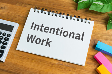 Intentional work concept on notepad with calculator and green plant on wooden desk